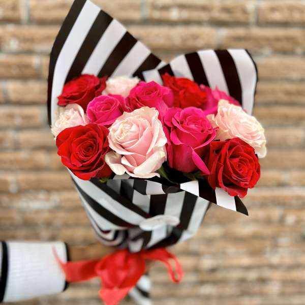Bouquet of red, pink, and white roses wrapped in black-and-white striped paper