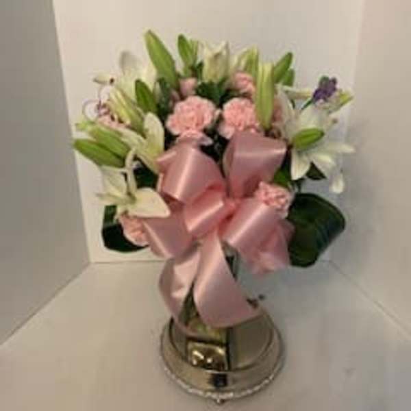 Pink and white flower arrangement with a large satin bow in a metal vase