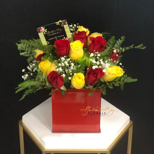 Red and yellow roses in a red square vase