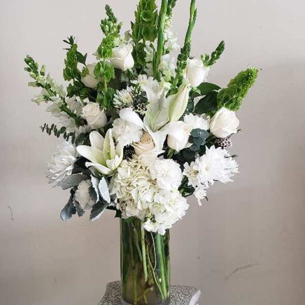White floral arrangement in a clear glass vase on a pedestal