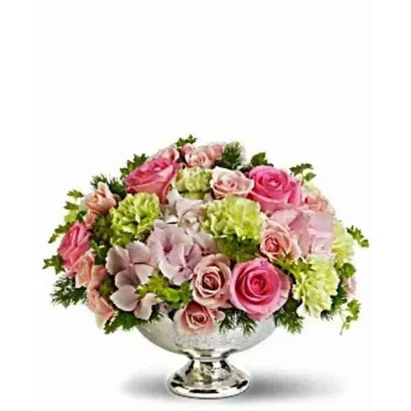 Low round arrangement of pink roses, green blooms, and pale hydrangeas in a silver pedestal bowl