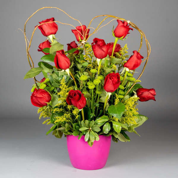 Red roses in a pink pot with a decorative twig arch