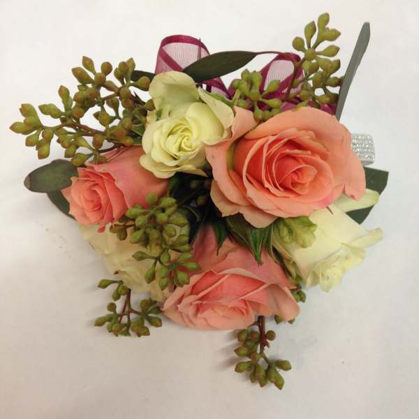 Small bouquet of peach and cream roses with green berries