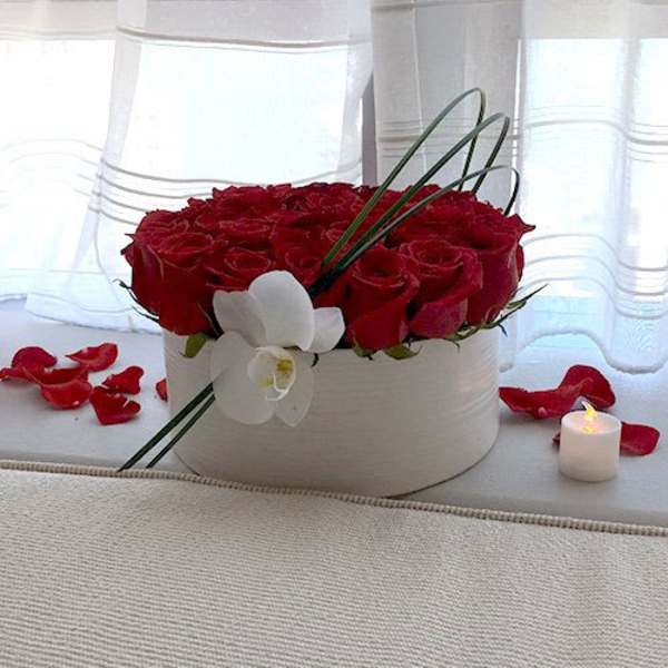 Red roses in a white round box with a white orchid accent