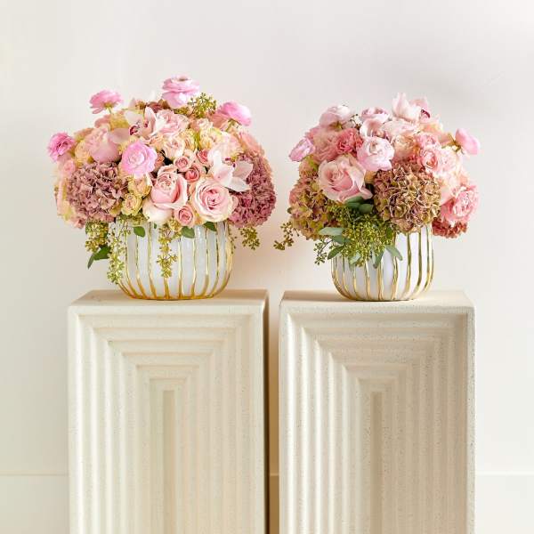 Two pink floral arrangements in gold wire vases on pedestals