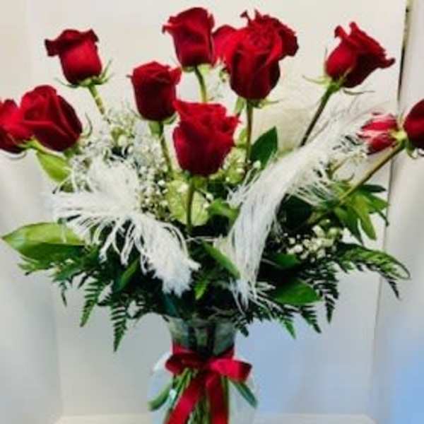 Bouquet of red roses in a clear glass vase with white feathers