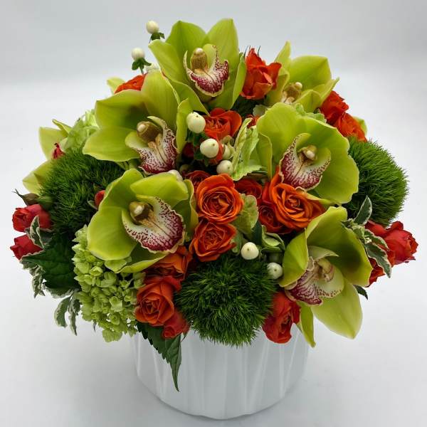Bouquet of green orchids and orange roses in a white vase