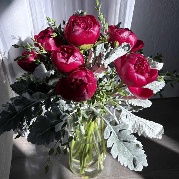 Bouquet of deep pink peonies in a clear glass vase
