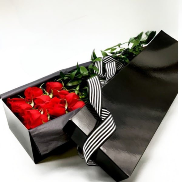Red roses in a black gift box with a striped ribbon
