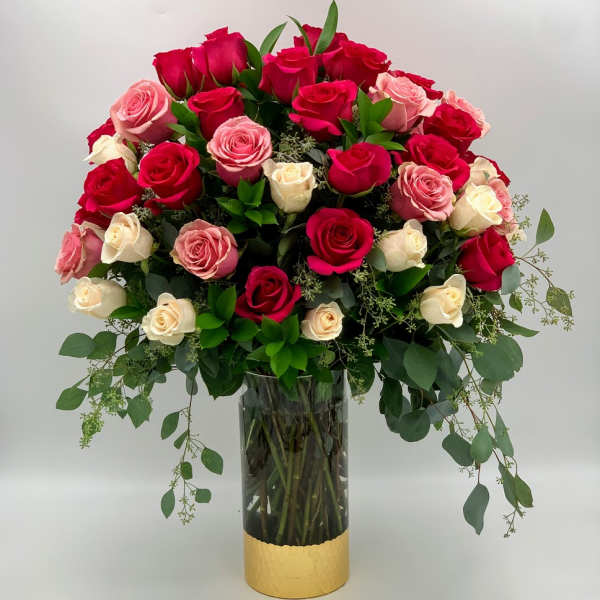 Bouquet of red, pink, and cream roses in a tall glass vase