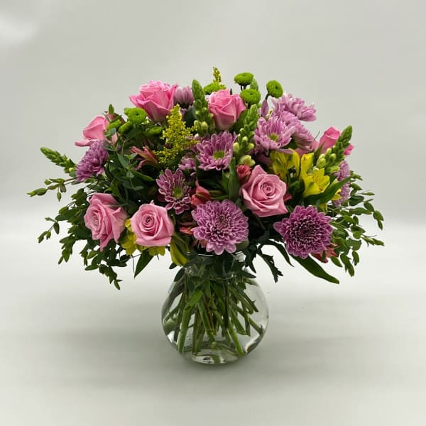 Pink roses and purple chrysanthemums in a clear glass vase