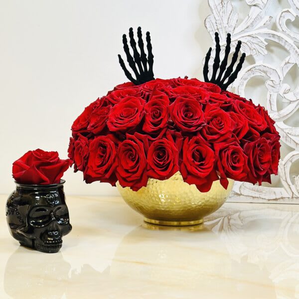 Red rose arrangement in a gold bowl with black decorative accents.
