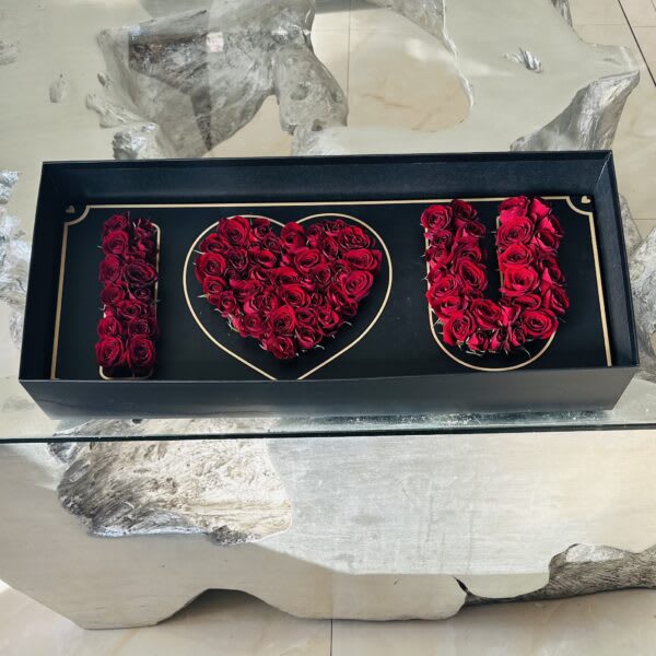 Black box with red roses arranged to spell "I ♥ U"