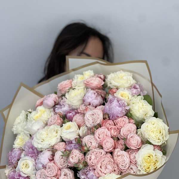 Large bouquet of pink, white, and lavender roses wrapped in cream paper