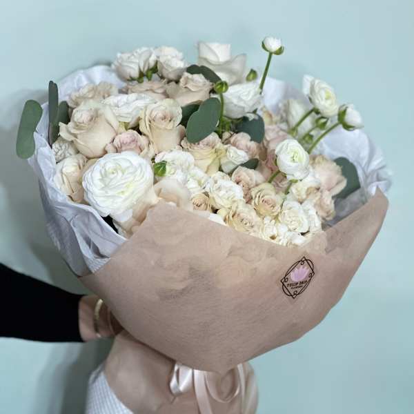 Bouquet of white and blush roses wrapped in beige paper