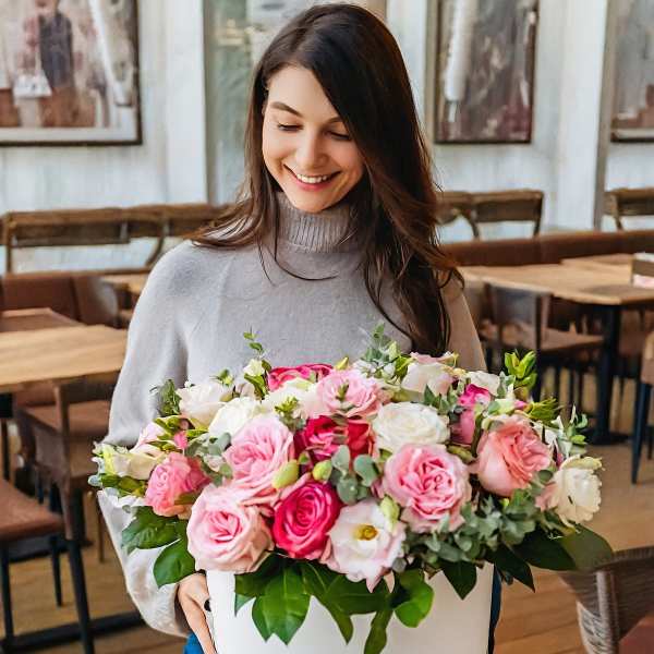 Woman holding a large box of pink and white roses