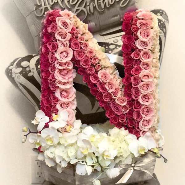 Pink rose arrangement shaped like the letter N with white orchids at the base.