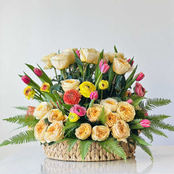 Basket arrangement of cream and pink roses with tulips and ferns