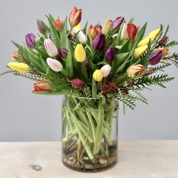 Mixed tulips in a clear glass vase with pebbles