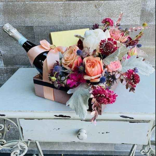 Flower arrangement in a gift box with a champagne bottle