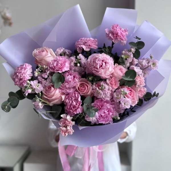 Pink bouquet of roses and carnations wrapped in lavender paper
