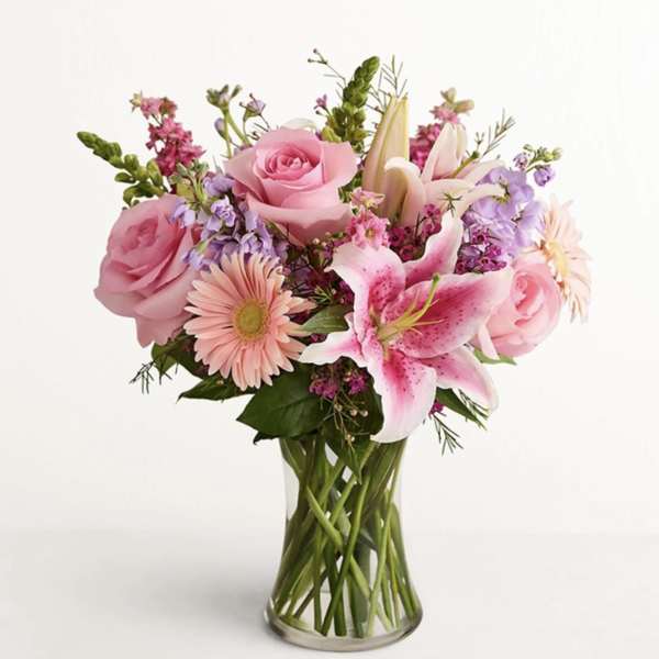 Pink roses and lilies arranged in a clear glass vase