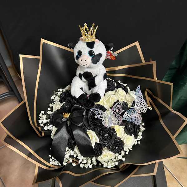Bouquet of black and white roses with a plush cow topper