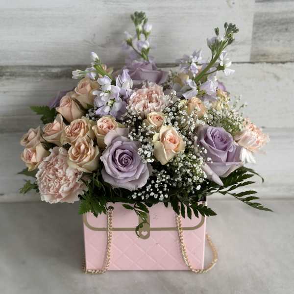 Pastel rose bouquet in a pink box with gold chain handles