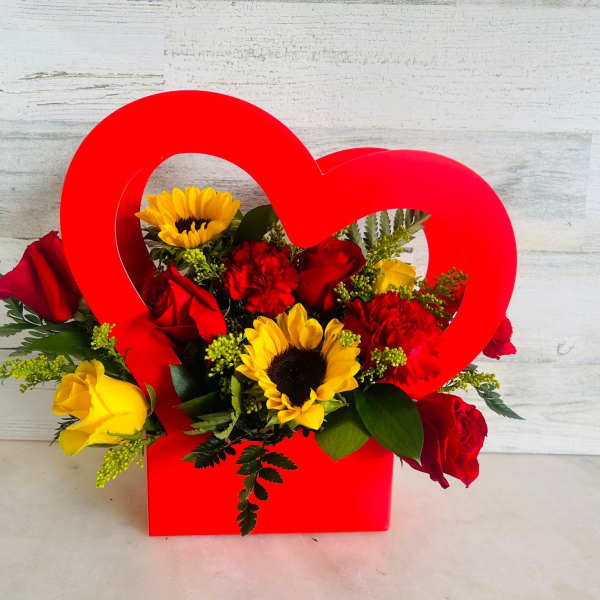 Red heart-shaped box filled with roses, sunflowers, and carnations