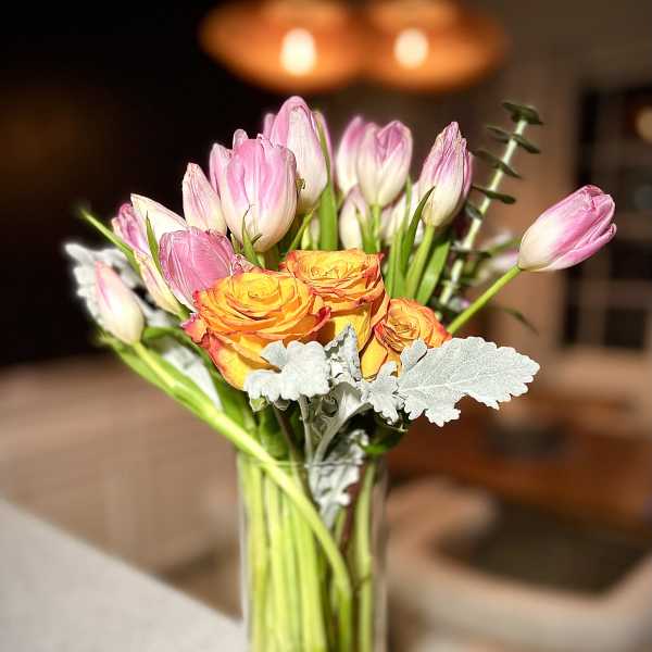 Pink tulips and orange roses in a clear glass vase