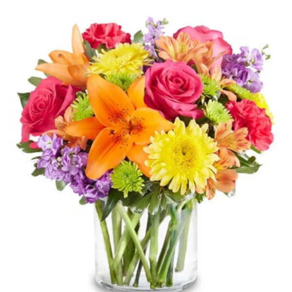 Mixed bouquet of roses, lilies, and daisies in a clear glass vase