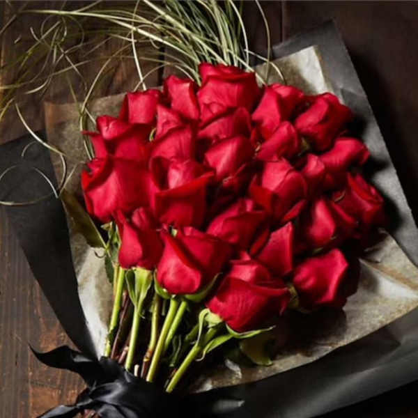 Bouquet of red roses wrapped in dark paper with a black ribbon