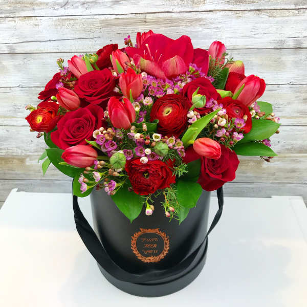 Red roses and tulips arranged in a black hatbox