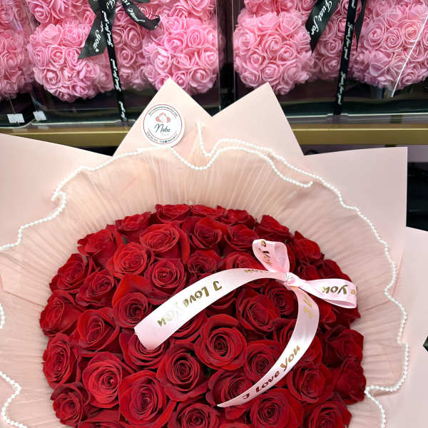 Bouquet of red roses wrapped in pale pink paper with a ribbon