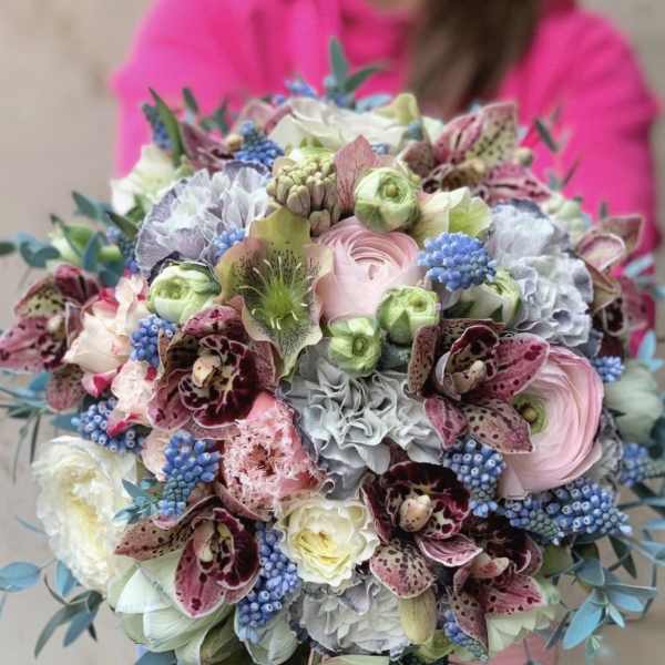 Pastel bouquet with orchids, ranunculus, and blue berry-like accents