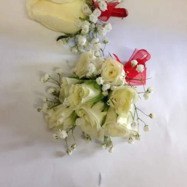 Two ivory rose bouquets with baby's breath and red ribbon accents