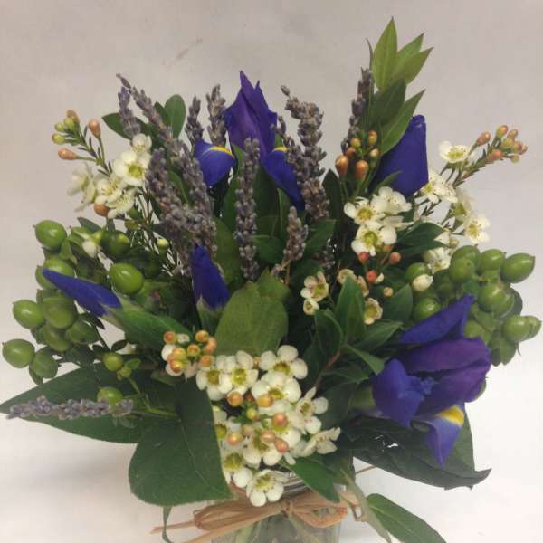 Blue iris bouquet with white blossoms in a glass jar