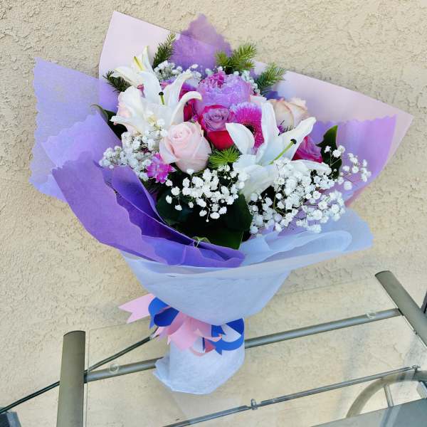Bouquet of pink and white flowers wrapped in lavender paper
