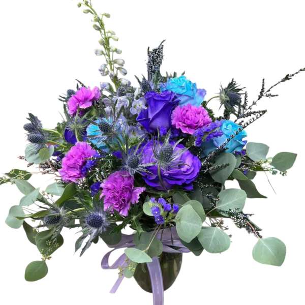 Purple and blue floral arrangement in a vase with eucalyptus