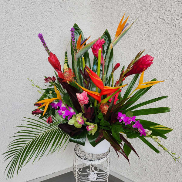 Tropical flower arrangement with bird of paradise and orchids in a white vase
