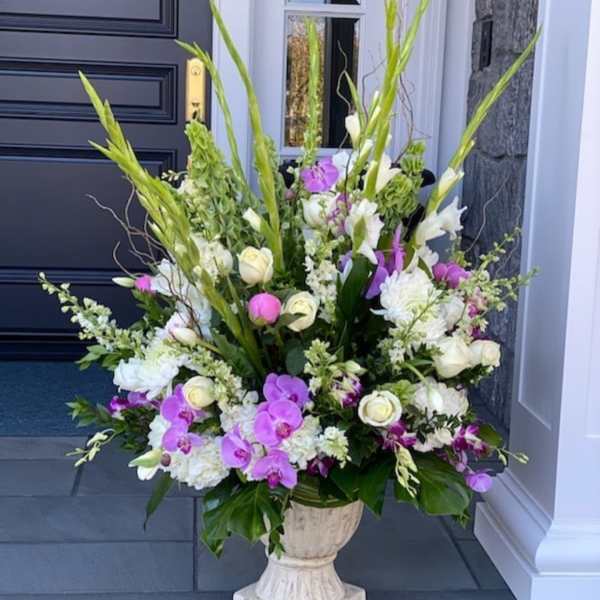 Tall floral arrangement with white and purple blooms in a pedestal urn