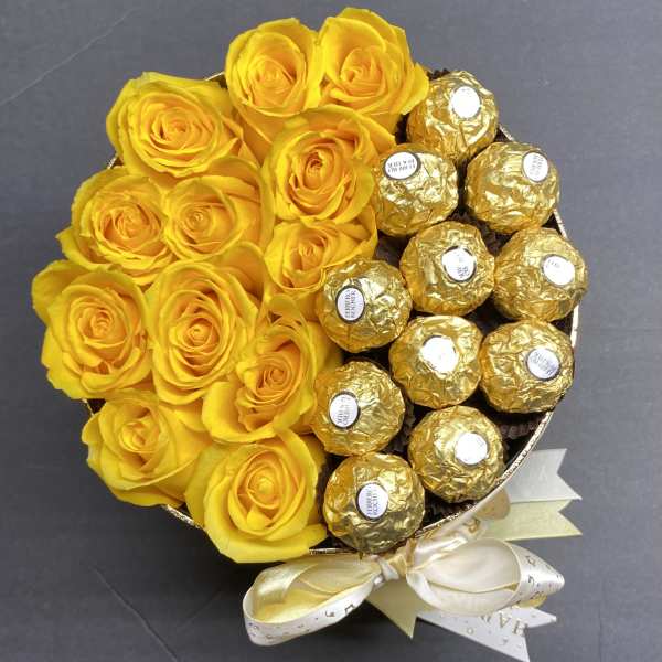 Yellow roses arranged with gold-wrapped chocolates in a round bouquet