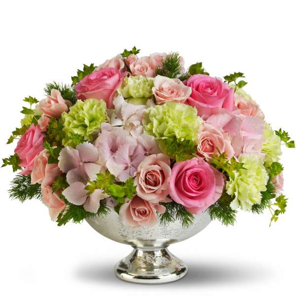 Pink and peach roses with green carnations in a silver pedestal bowl