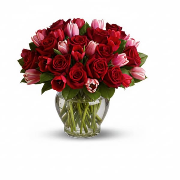 Red roses and pink tulips arranged in a clear glass vase