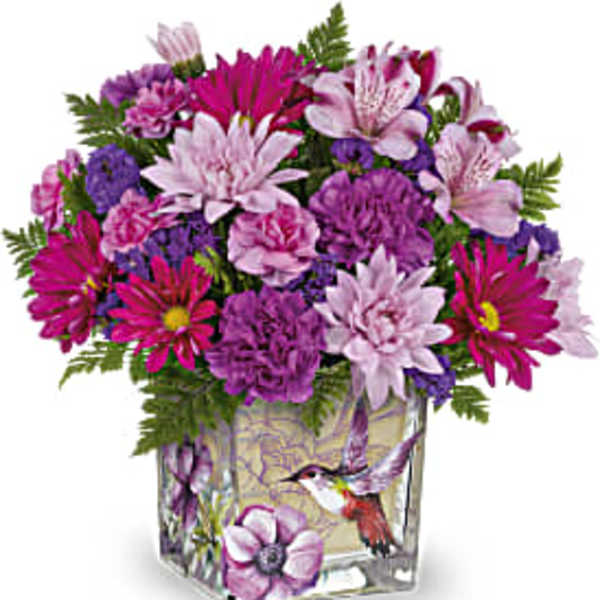 Pink and purple mixed bouquet in a square glass vase with a hummingbird design