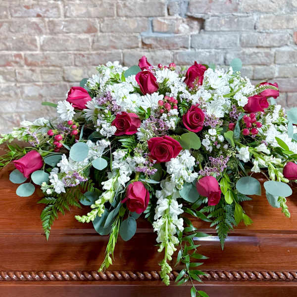 Casket spray with pink roses, white flowers, and greenery