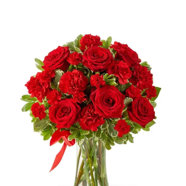 Red roses and carnations in a clear glass vase with a red ribbon