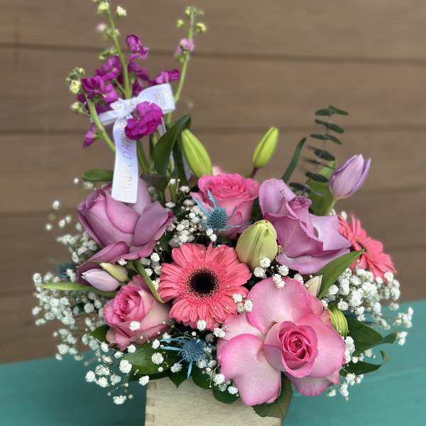 Pink and lavender bouquet with roses, gerbera daisy, and lilies in a wooden box