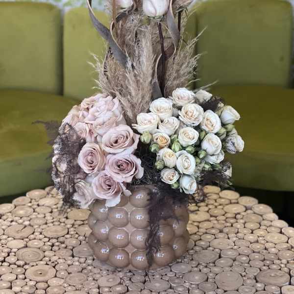 Pink and white rose arrangement in a textured vase with dried grasses