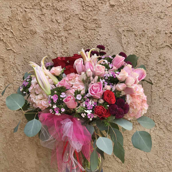 Pink and red rose bouquet with lilies in a glass vase